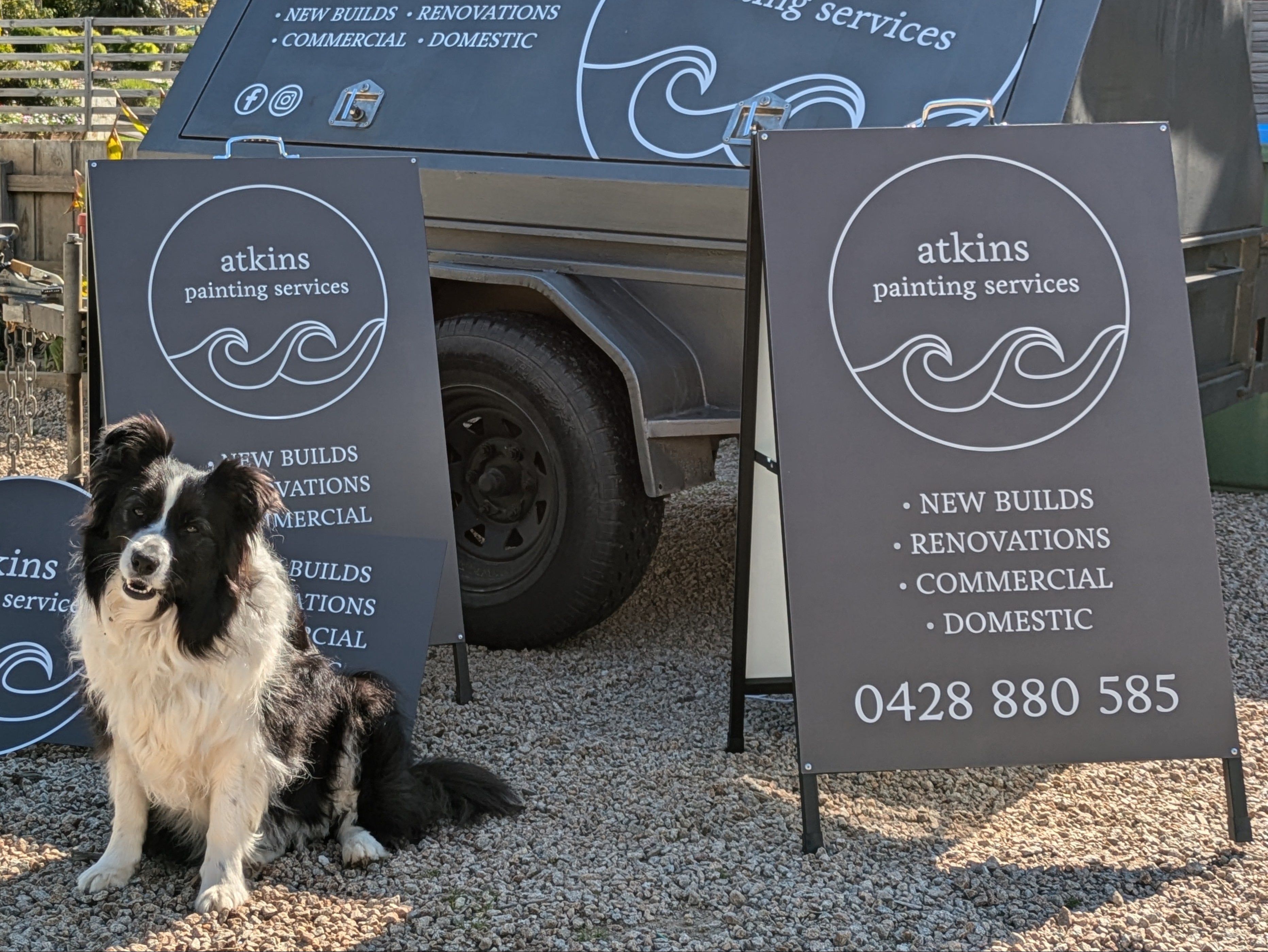 Dog standing in front of a sign written trailer and A-frame sign for 'atkins painting services' by Saltwater Sign Co.
